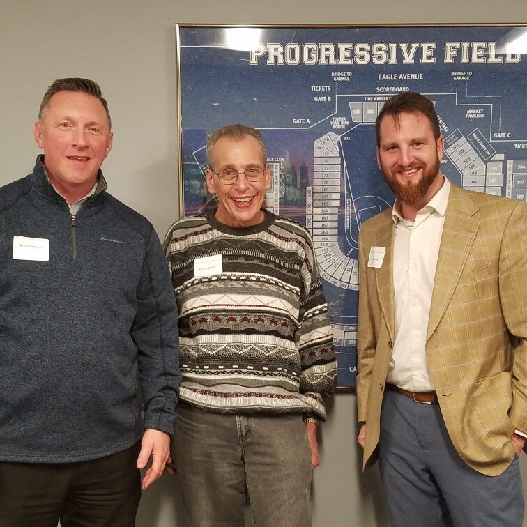 Three men standing in front of a sign.